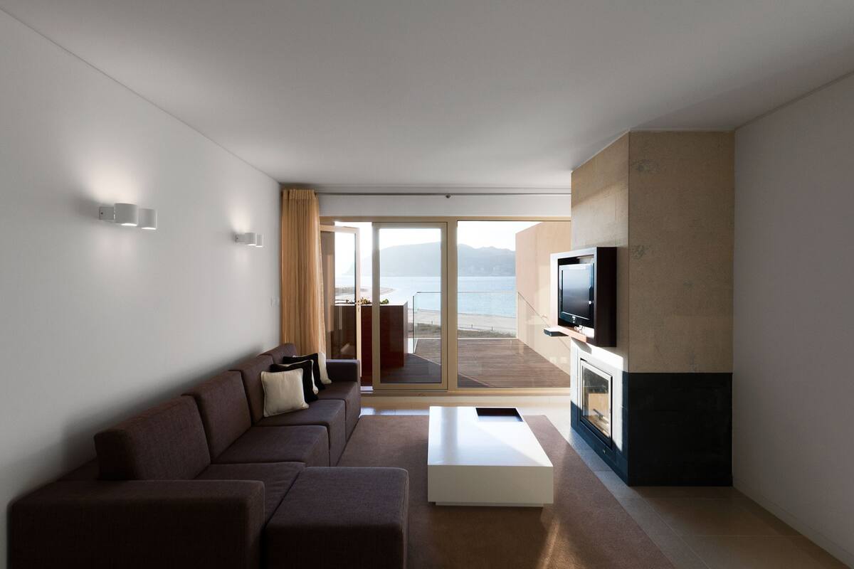 A modern living room with a sofa, coffee table, flat-screen TV, and a fireplace.