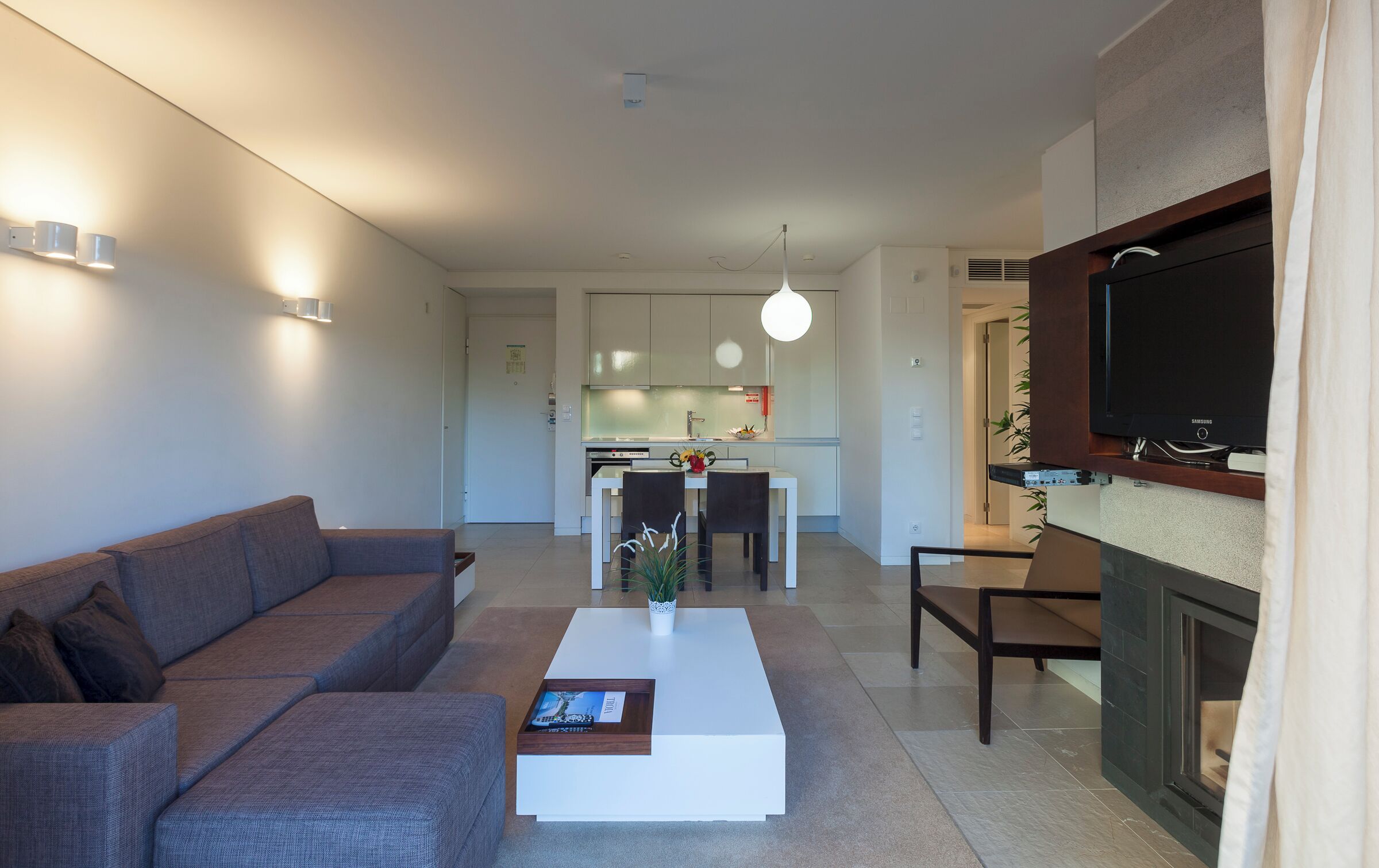 A modern living room with a sofa, coffee table, and a flat-screen TV mounted on a wall.