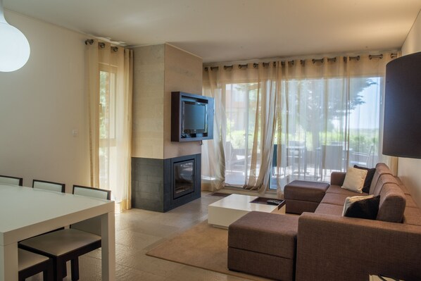 Uma sala de estar com lareira, televisão, sofá e mesa de jantar.