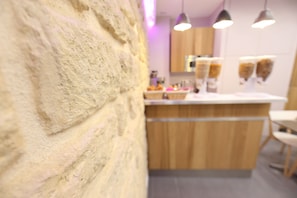 A modern kitchen with wooden cabinets, a white countertop, and pendant lighting. - Sweet Hotel (Paris)