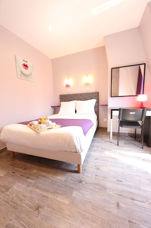 A bedroom with a bed, bedside table, desk, chair, and a wall-mounted mirror. - Sweet Hotel (Paris)