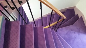 A staircase with purple carpeted steps and black metal railings. - Sweet Hotel (Paris)