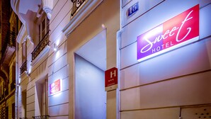 A hotel entrance with a neon sign, a visible room number, and a sign indicating the hotel has 3 stars. - Sweet Hotel (Paris)