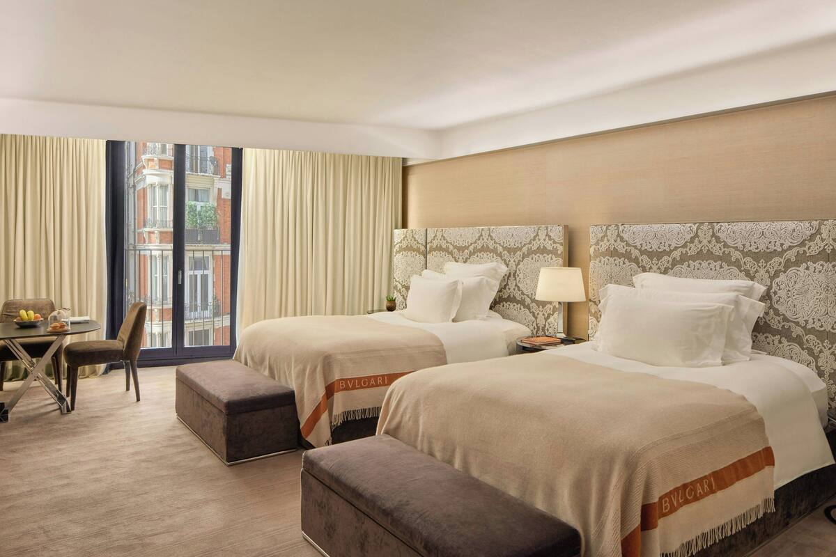 A hotel room with two beds, a desk, and a chair.
