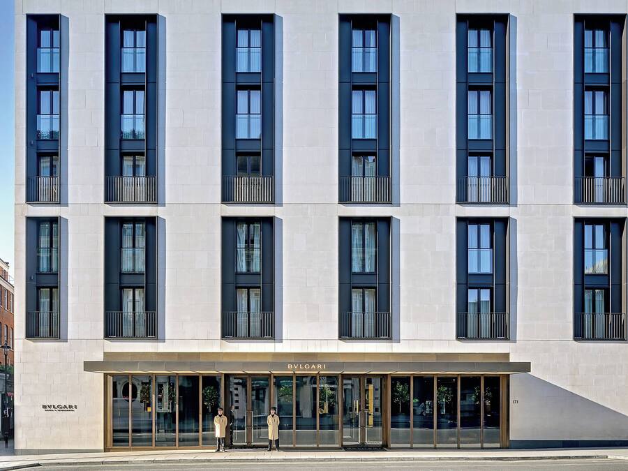 Un edificio moderno con una tienda BVLGARI en la planta baja, que cuenta con grandes ventanales y un diseño limpio y minimalista.