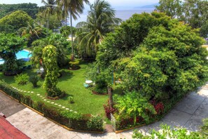 A lush garden with a pool, palm trees, and a view of the ocean. - Hotel Posada Koniapan (Catemaco)