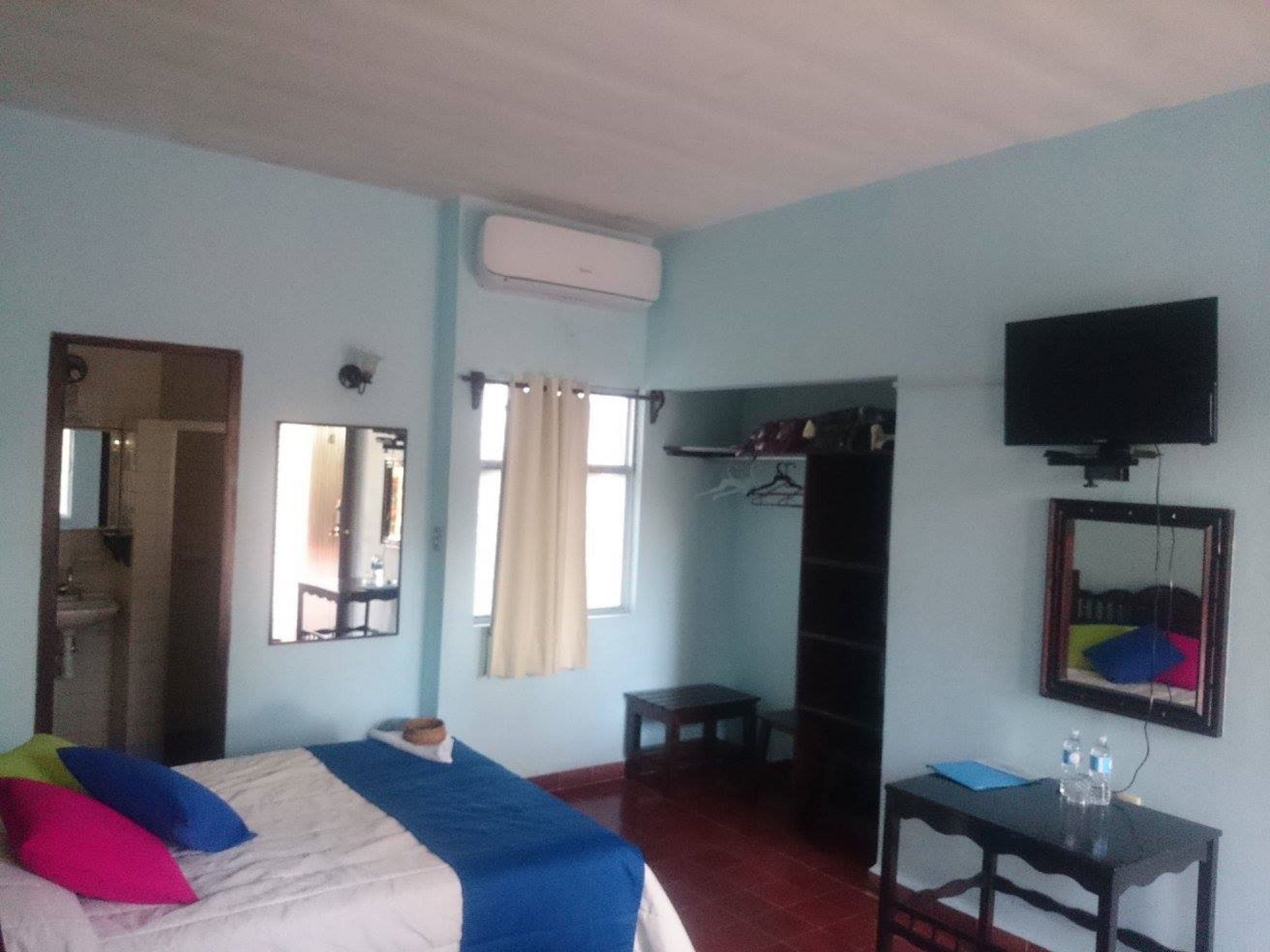 A hotel room with a bed, a small table, a TV, and a wardrobe.
