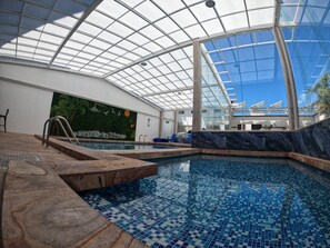 An indoor swimming pool with a glass ceiling, tiled floor, and a mural wall. - Hotel Senorial Tlaxcala (Tlaxcala)
