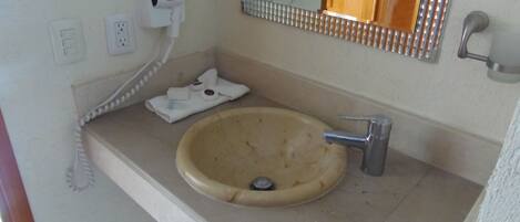 Un baño con un lavabo color beige, un espejo, una toalla y un teléfono.