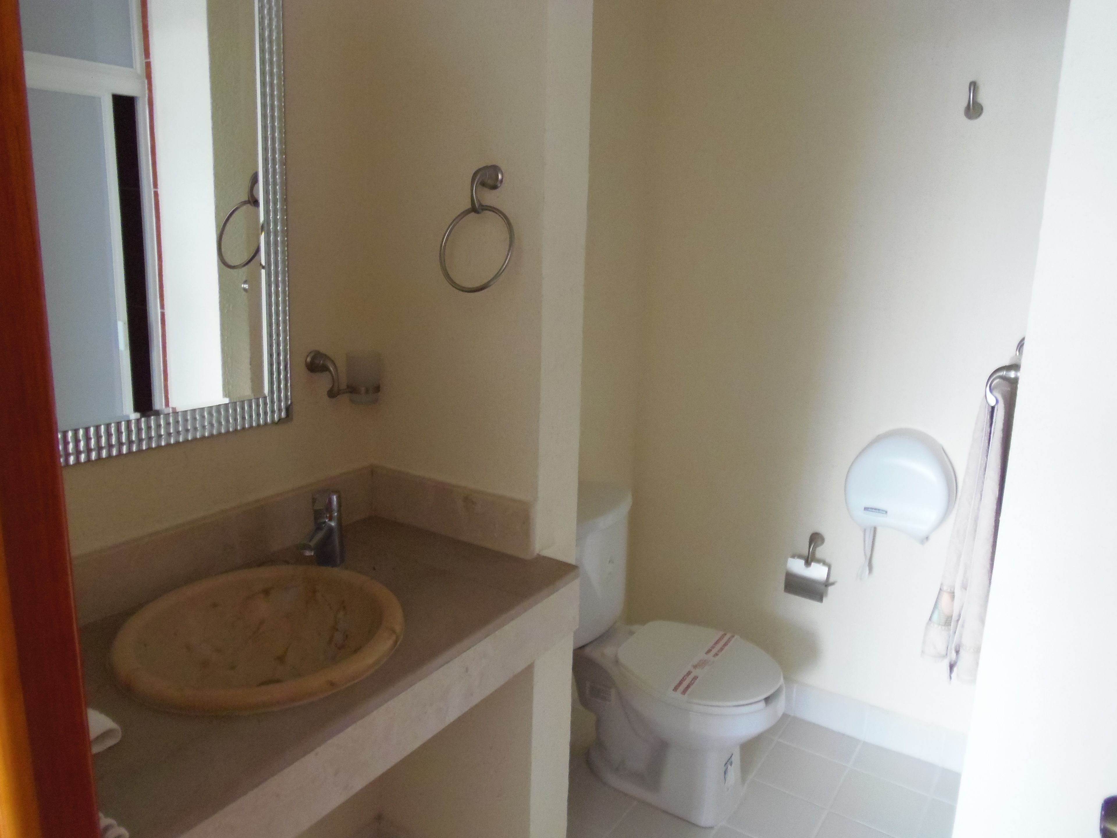 A bathroom with a sink, toilet, and mirror.