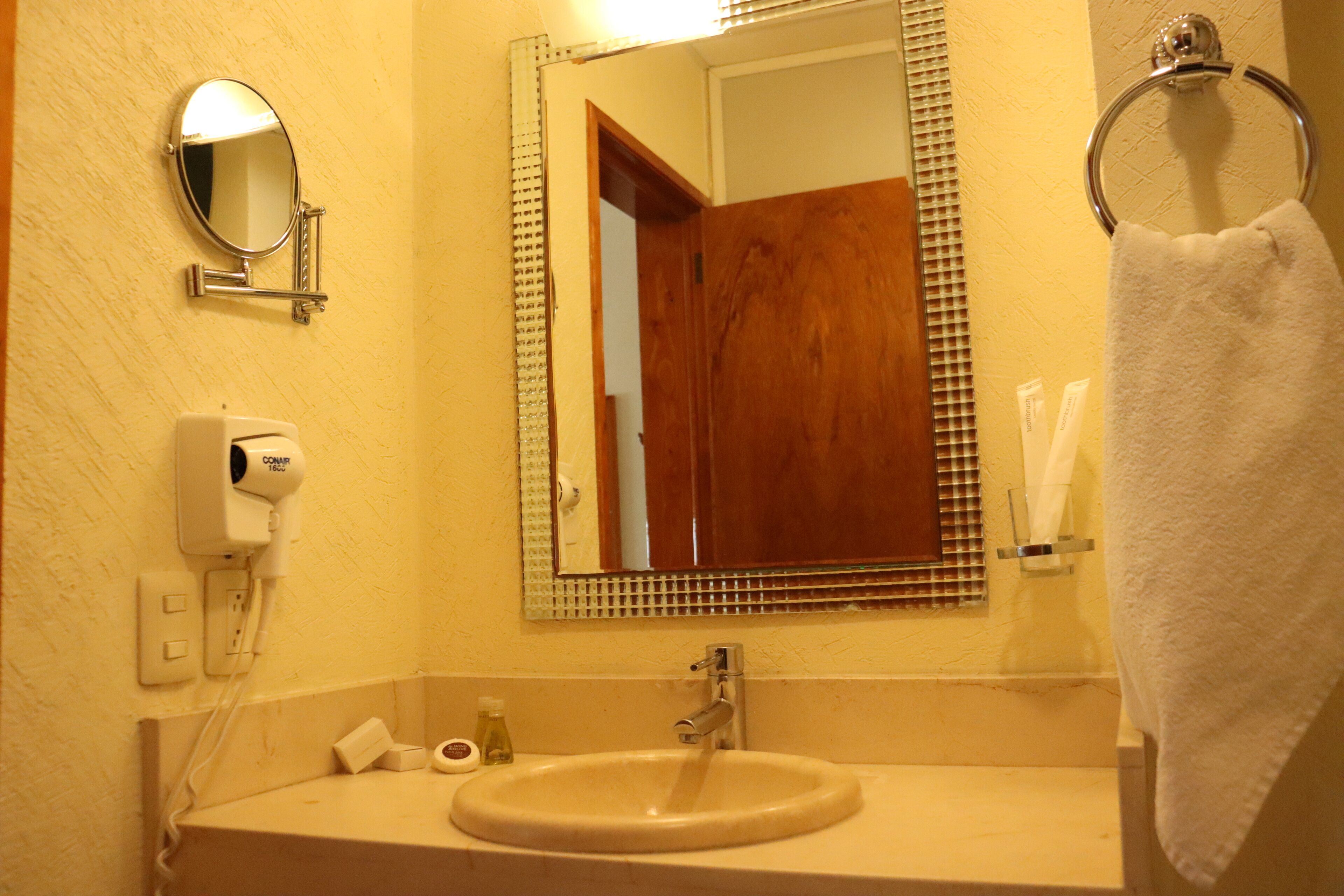 A bathroom with a sink, mirror, towel rack, and toiletries.