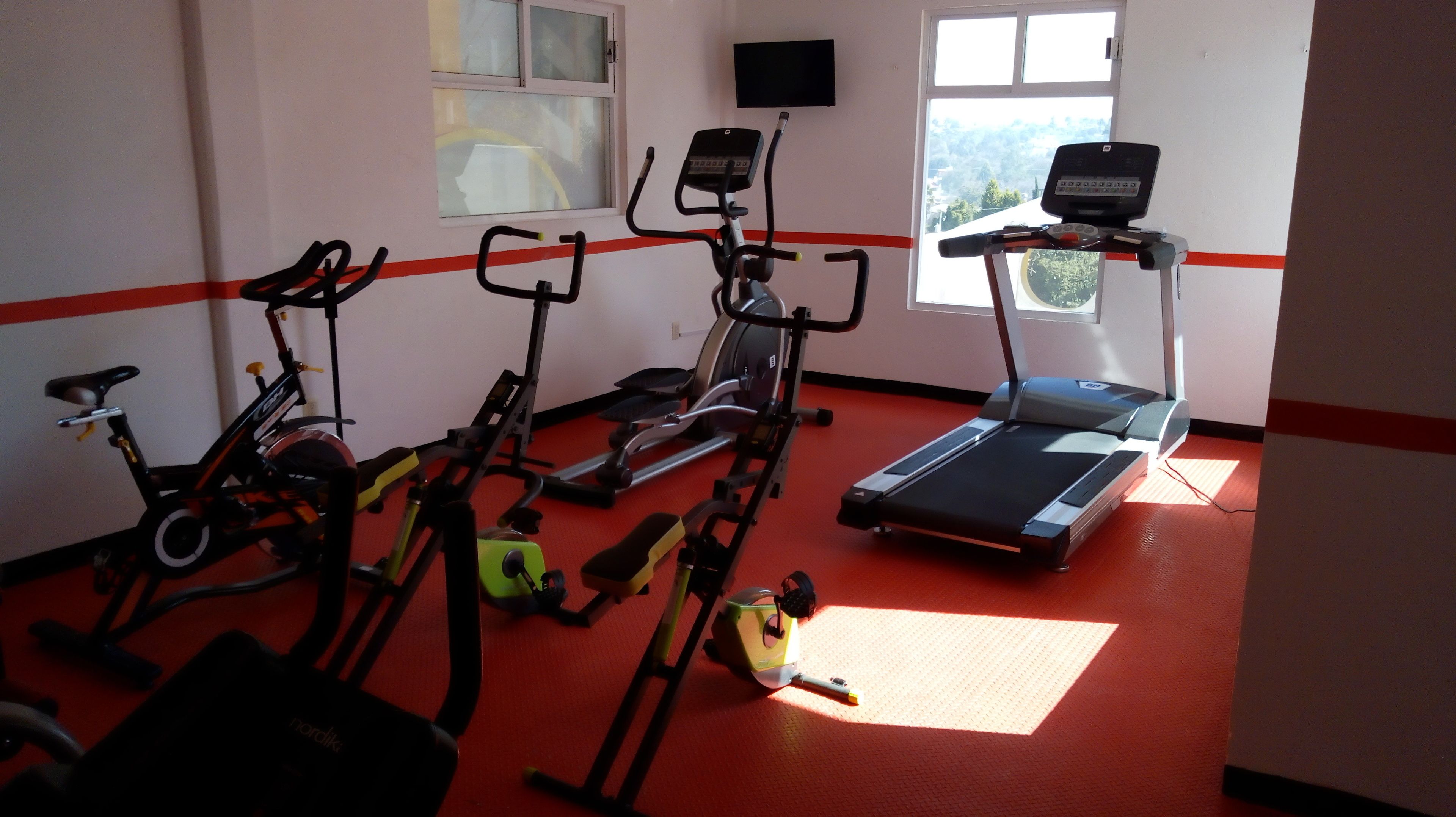Un gimnasio con bicicletas estáticas, cinta de correr y equipo de ejercicio.