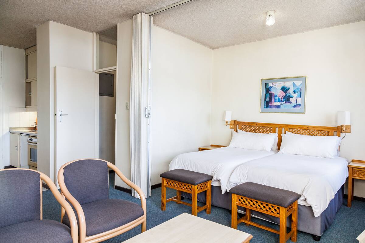 Ett hotellrum med en dubbelsäng, två sängbord, ett skrivbord med en stol och en garderob.