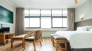 A hotel room with a bed, two chairs, a TV, and a large window. - Gardens Centre Holiday Apartments (Cape Town)