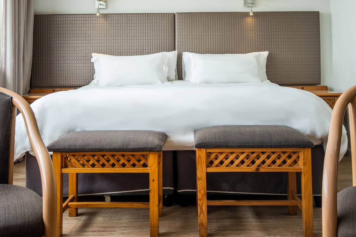 Ett hotellrum med en säng, två sängbord, en takfläkt och två väggmonterade lampor.
