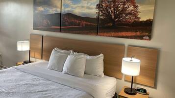 A neatly made bed with white linens, two bedside lamps, and a wall-mounted clock.