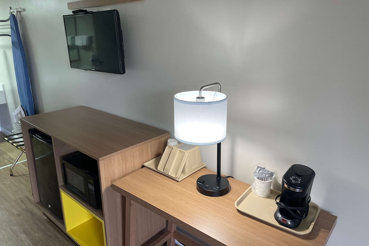 Eine Küchenzeile mit einer Mikrowelle, einer Kaffeemaschine und einer Lampe auf einer Holzausziehtafel.