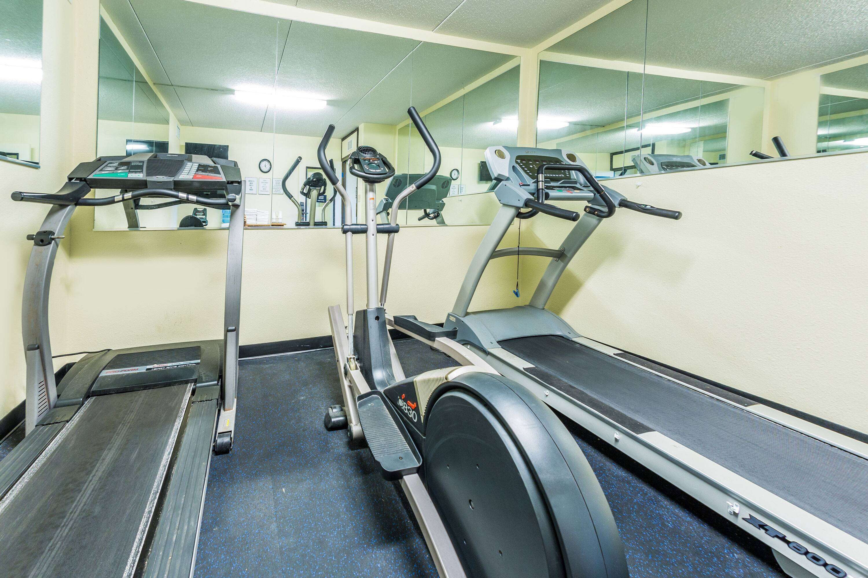 Un gimnasio con cintas de correr, elípticas y bicicletas estáticas.