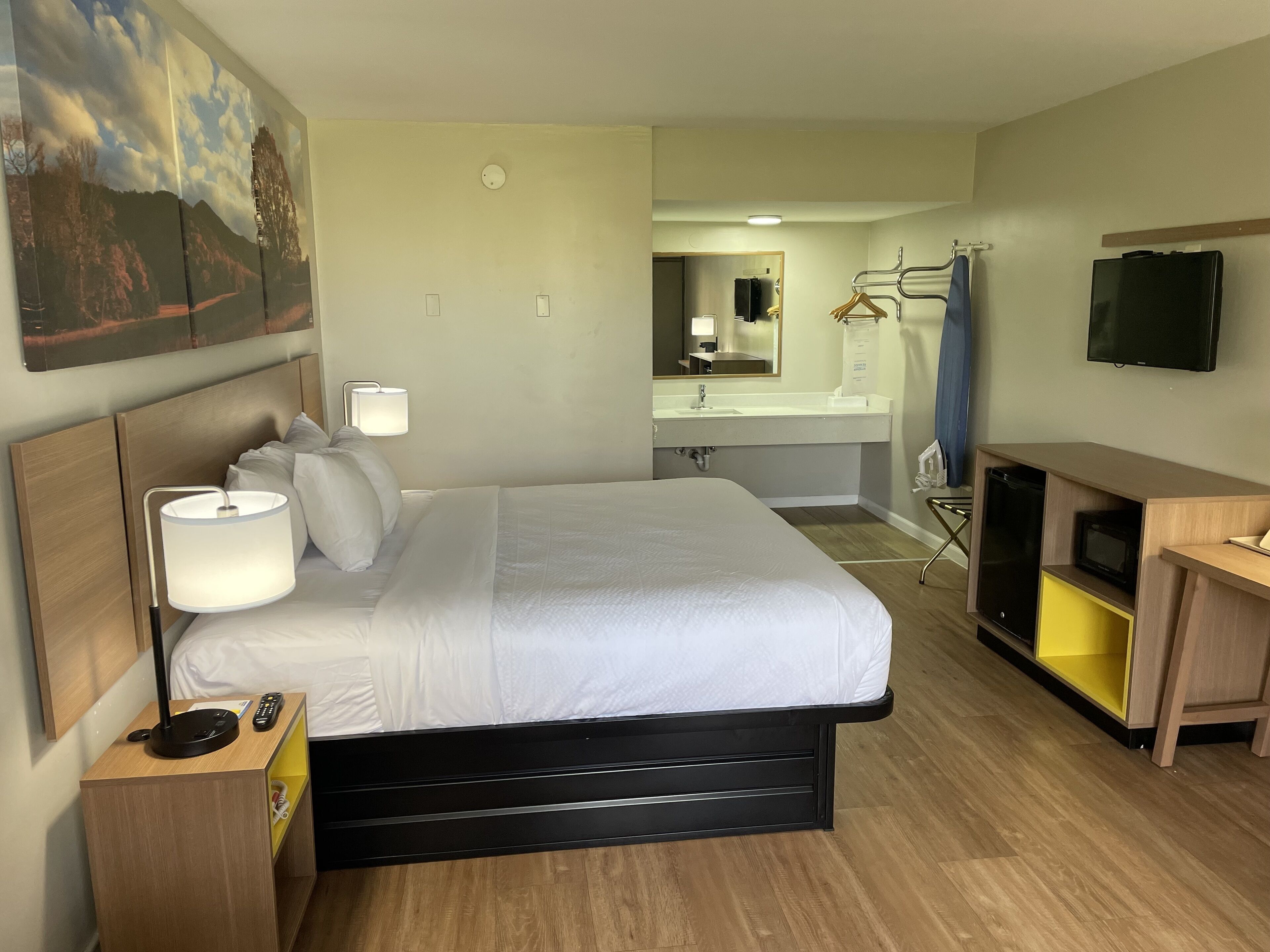 Une chambre d’hôtel équipée d’un lit, d’une lampe de chevet, d’une télévision et d’un bureau avec un ordinateur.