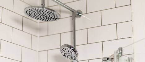 A shower with a handheld showerhead and a fixed showerhead mounted on a wall.