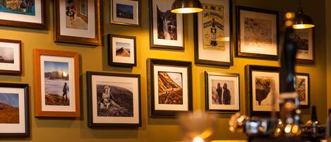 A wall with multiple framed photographs, some with text, and two hanging pendant lights.