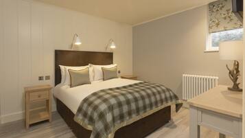 A bedroom with a bed, bedside tables, a lamp, a radiator, and a window with curtains.