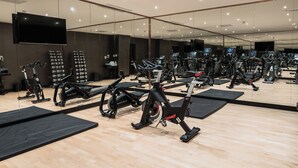 A gym with various exercise machines, a large mirror, and a flat-screen TV. - Montcalm Brewery Townhouse (London)