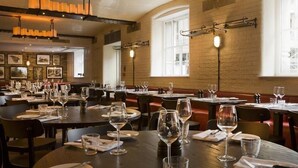 A restaurant with multiple tables and booths, each set with wine glasses and cutlery. - Montcalm Brewery Townhouse (London)
