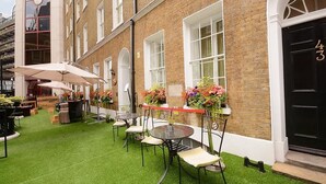 An outdoor seating area with tables and chairs, surrounded by brick walls and windows. - Montcalm Brewery Townhouse (London)
