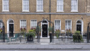 A two-story brick building with a black entrance gate, numbered doors, and a black metal fence. - Montcalm Brewery Townhouse (London)