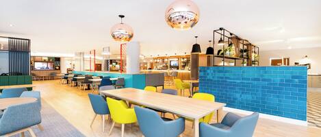 Un restaurante moderno con una zona de bar, mesas de madera y sillas coloridas.
