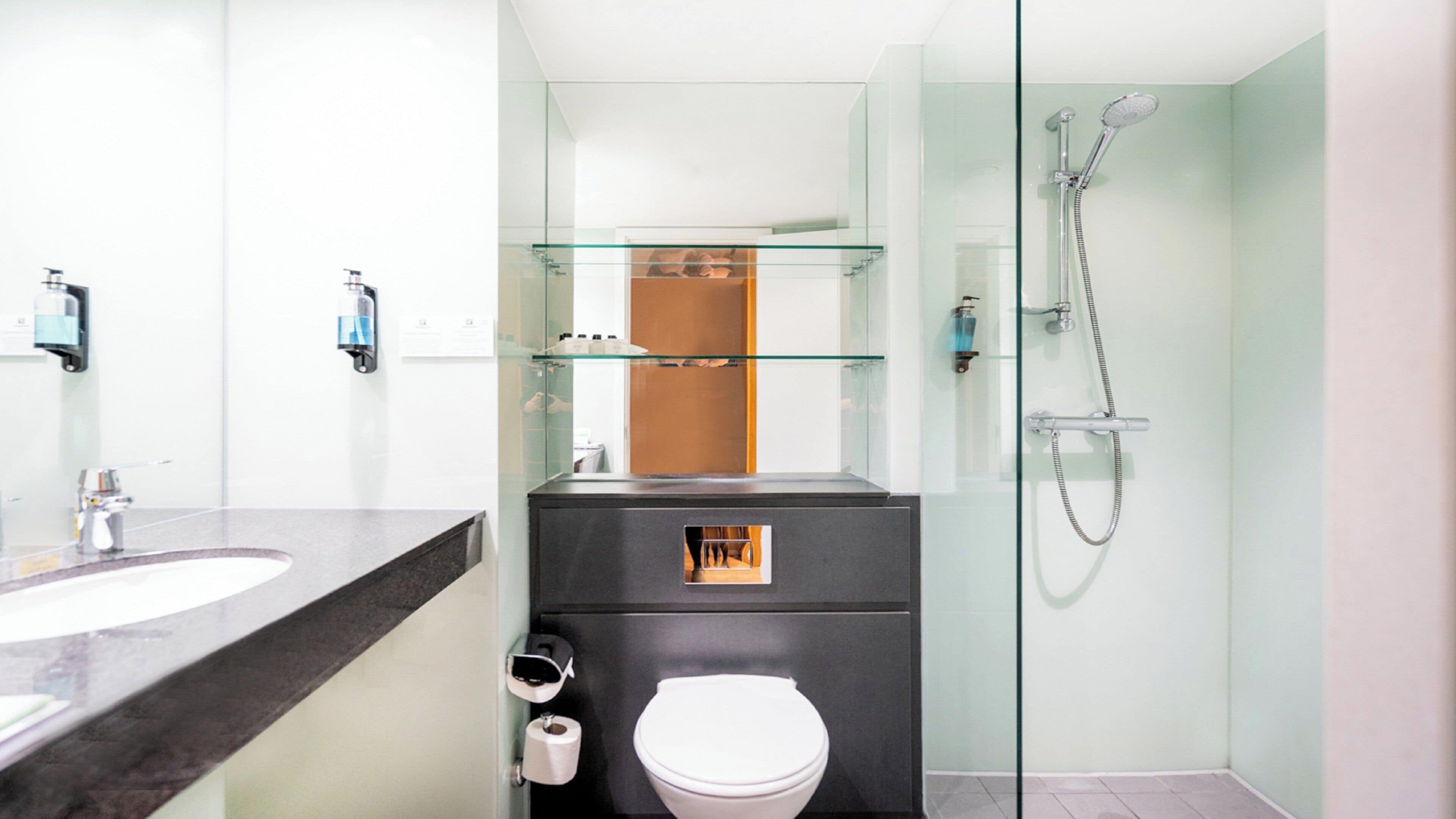 Une salle de bain moderne avec une douche à parois de verre, des toilettes et un meuble-lavabo avec un miroir.