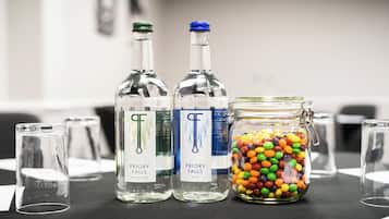 Dos botellas de agua con gas Priory Falls y un tarro de caramelos de colores sobre una mesa.
