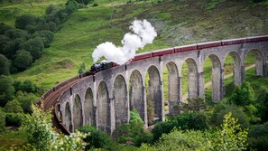 A steam train crossing a stone viaduct over a lush green valley. - Holiday Inn London - Luton Airport by IHG (Luton)