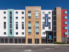 Un hôtel Travelodge à plusieurs étages, doté d’une façade moderne, de grandes fenêtres et d’une enseigne Travelodge bien visible.