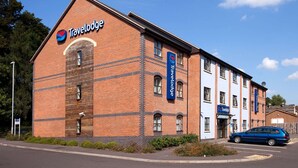 A Travelodge hotel with a brick facade, multiple windows, and a parking area with a blue car. - Travelodge Kidderminster (Kidderminster)