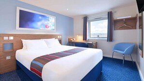 A hotel room with a large bed, a desk, a chair, a TV, and a window with curtains. - Travelodge Kidderminster (Kidderminster)