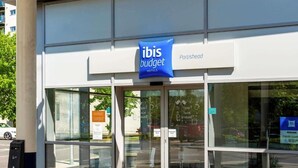 A modern building with a glass facade and a blue sign for ibis budget hotels. - go2 portishead marina hotel (Bristol)