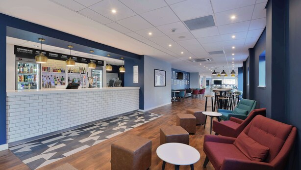 A modern lounge area with a bar, seating, and a patterned floor.