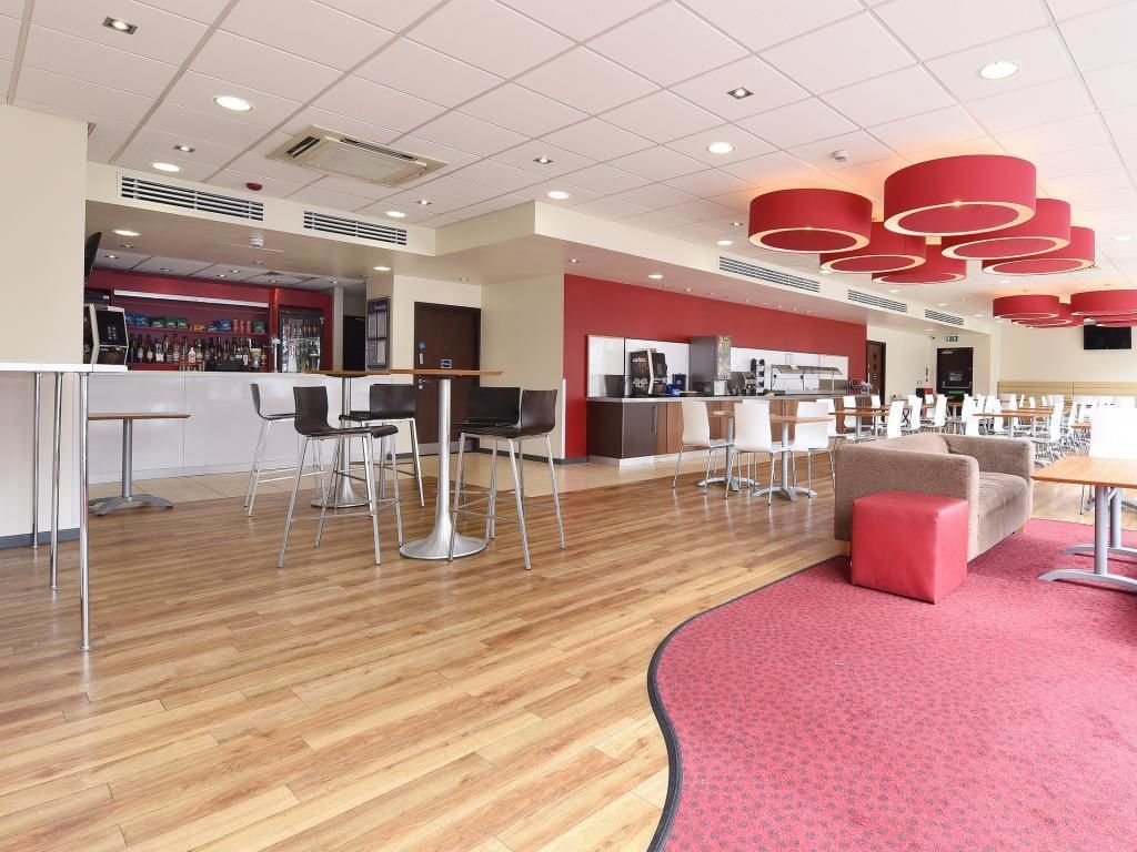 A modern hotel lobby with a bar area, seating arrangements, and a red accent wall.