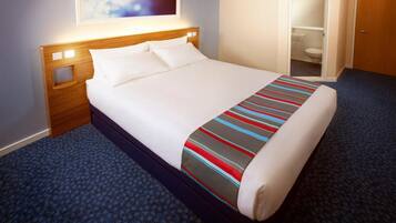 A hotel room with a bed, a nightstand, a window with a view, and a door leading to a bathroom.