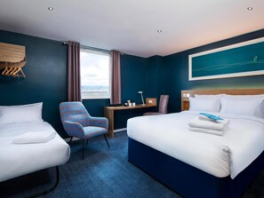 A hotel room with a bed, two chairs, a desk, and a window with curtains. - Travelodge Bradford Central (Bradford)