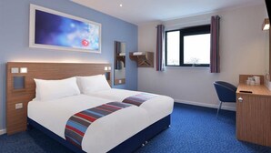 Ein Hotelzimmer mit einem großen Bett, einem Schreibtisch, einem Sessel, einem Fenster mit Vorhängen und einem Bild an der Wand.