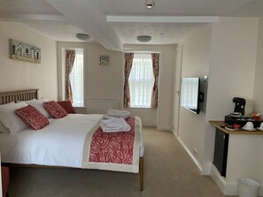 A hotel room with a bed, a TV, a coffee machine, and a view of the outside. - The Clarence (Weymouth)