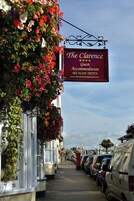A hotel sign with a flower display and parked cars.