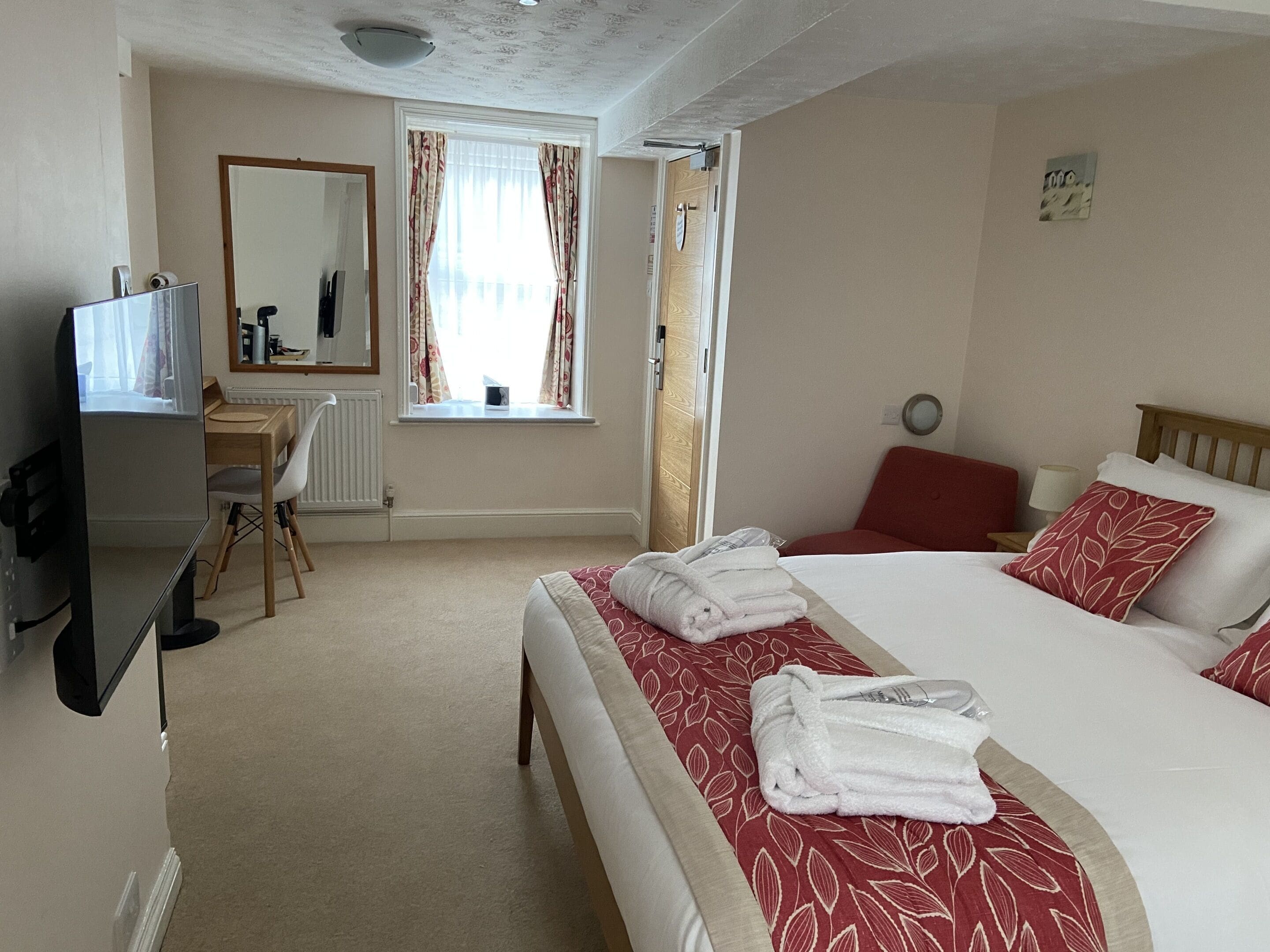 A hotel room with a bed, a desk, a chair, and a window with curtains.