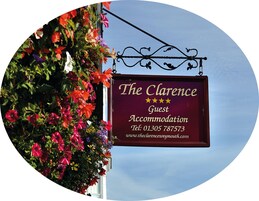 A sign for The Clarence Guest Accommodation with contact information and a website URL.