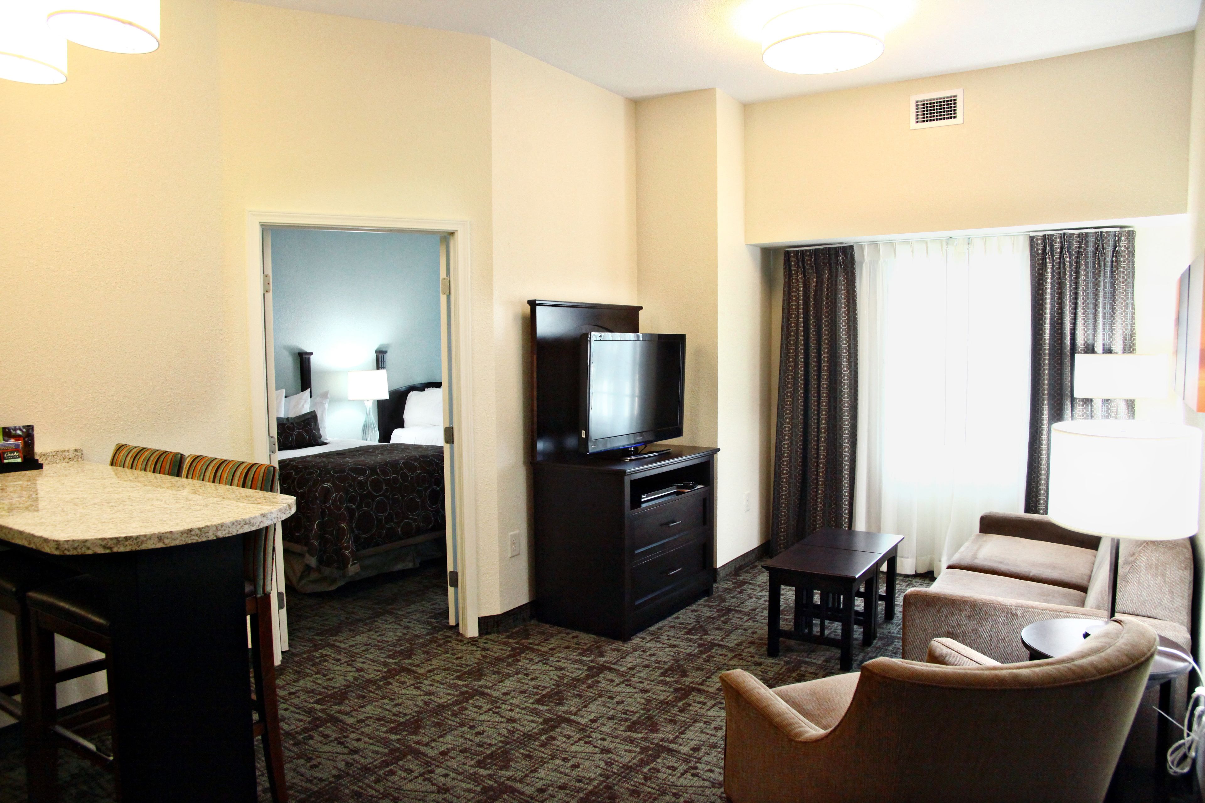 A hotel room with a kitchenette, a television, a sofa, and a bed.