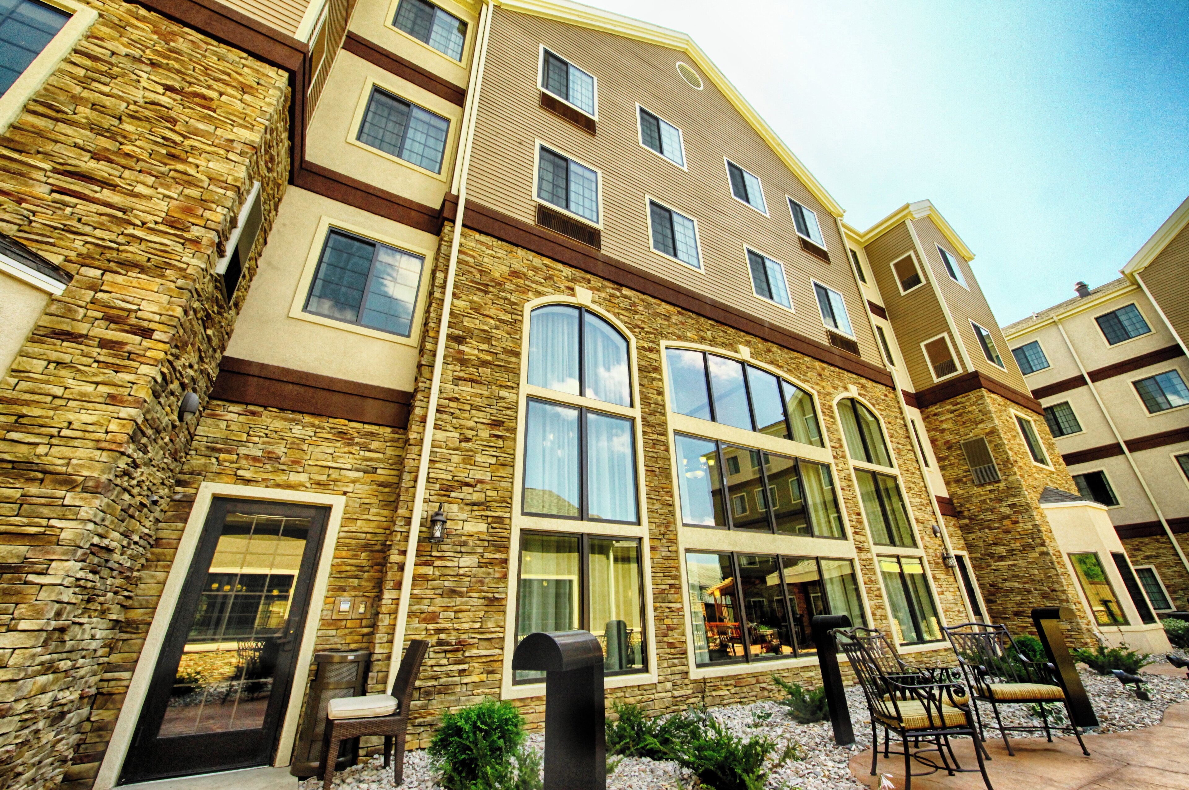 A multi-story building with stone and wood exterior, large windows, and outdoor seating.