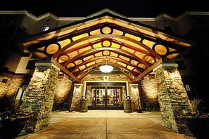 A hotel entrance with a stone facade, a wooden archway, and a large door.